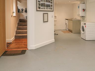 A utility room with a washing machine and dryer next to a sink and countertop at River Cottage in Morpeth