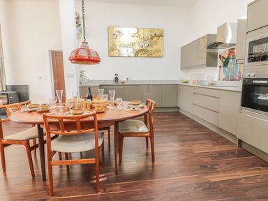 A kitchen with a wooden dining table and chairs set with dishes and glasses at Chy Lagen Hos in Newquay