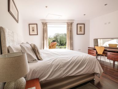 A bedroom with a bed a lamp and a wooden desk with chair near a window at Chy Lagen Hos in Newquay