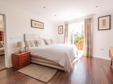 A bedroom with a bed bedside table lamp framed pictures and curtains at Chy Lagen Hos in Newquay