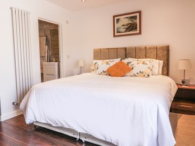 A bedroom with a double bed white bedding floral pillows and lamps on bedside tables at Chy Lagen Hos in Newquay