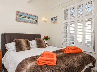 A bedroom with a double bed with brown pillows and orange towels on a brown blanket at Serendipity in Fowey