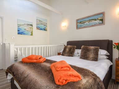 A bedroom with a bed that has fur cushions and orange towels on a fur blanket at Serendipity in Fowey