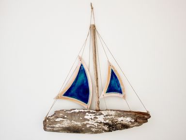 A wall hanging decoration of a sailboat with blue sails made from wood and string