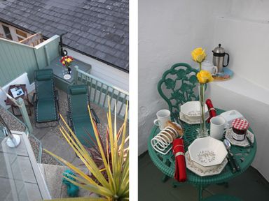 An outdoor patio with two green lounge chairs and a small table with flowers and plates at The Shell Seekers in Fowey