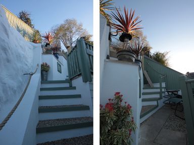 An outdoor staircase with green railings and potted plants on white walls at The Shell Seekers in Fowey