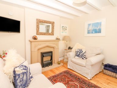 A living room with two armchairs fireplace mirror and wall-mounted tv at The Shell Seekers in Fowey