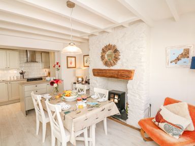 A dining area with a table set for breakfast and a kitchen in the background at The Shell Seekers in Fowey
