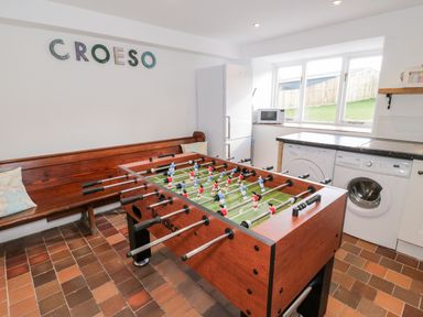 A game room with a foosball table a wooden bench a refrigerator washing machine and microwave at Cefn Nannau in Ty-nant near Cerrigydrudion