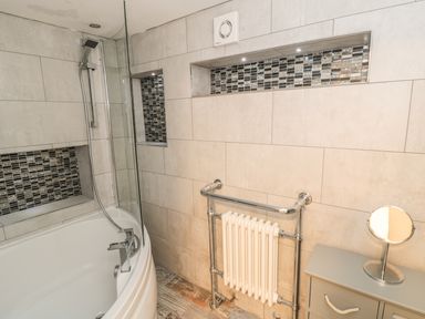 A bathroom with a bathtub shower combination radiator and a cabinet with mirror at 11A Church Street Whitby