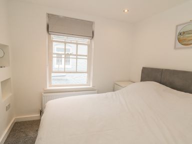 A bedroom with a bed a window a bedside table and a framed picture on the wall at 11A Church Street in Whitby