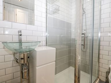 A bathroom with a glass sink and a shower with glass doors at 11A Church Street in Whitby