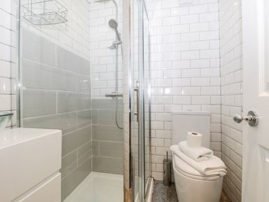A bathroom with a shower enclosure, toilet with towels and toilet paper, and a vanity unit at 11A Church Street Whitby