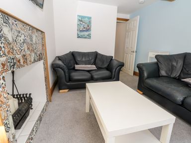 A living room with black sofas white coffee table and a tiled fireplace at 11A Church Street Whitby