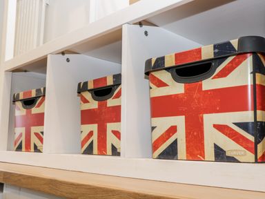 Three storage boxes with United Kingdom flag design on a white shelf at 11A Church Street in Whitby