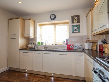 A kitchen with cabinets a sink a window and various kitchen items on the counter at Tides Reach in Rhosneigr