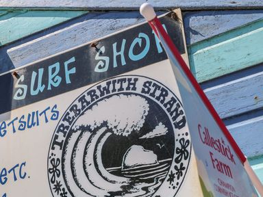 A surf shop sign on a wooden wall with blue and green paint at Gull Rock in Trebarwith Strand