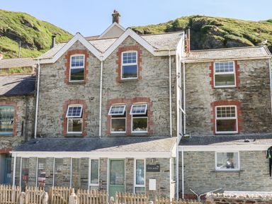 A stone house with multiple windows and a fenced front at Gull Rock in Trebarwith Strand