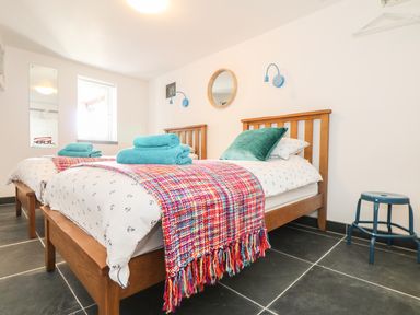 A bedroom with two wooden single beds with patterned bedding and towels at Gull Rock in Trebarwith Strand