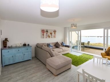 A living room with a sofa and dining table at Welymora Pwllheli