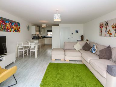 A living room with a sofa and dining area at Welymora Pwllheli