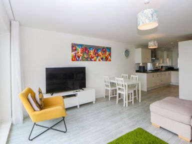 A living room with a television and dining set at Welymora Pwllheli