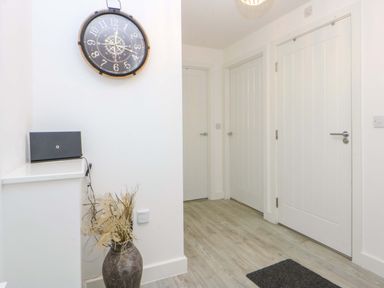 A hallway with a clock and a cabinet at Welymora in Pwllheli