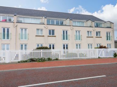 A building with multiple windows and a white fence at Welymora in Pwllheli