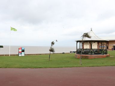 A grassy area near a body of water with a gazebo and a flagpole at Tilly's Retreat in Hunstanton