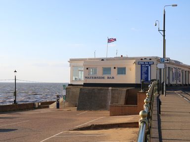 Waterside bar building near a waterfront with railings and parking area at Tilly's Retreat in Hunstanton