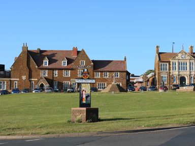A grassy area with a sign reading Hunstanton in front of brick buildings including the Golden Lion Hotel at Tilly's Retreat in Hunstanton