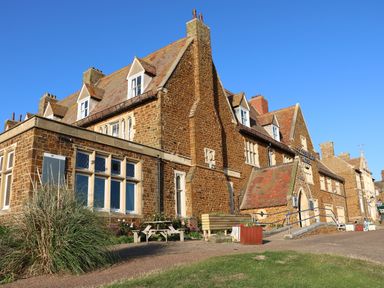 A large brick building with multiple chimneys and windows under a clear blue sky at Tillys Retreat in Hunstanton