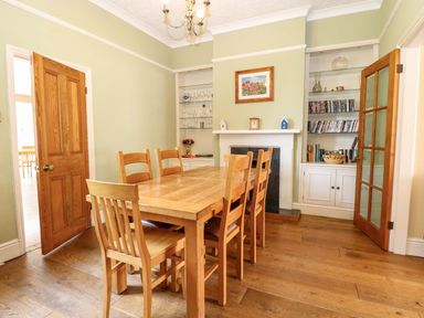 A dining room with a wooden table and chairs at Tilly's Retreat in Hunstanton