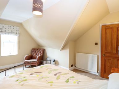 A bedroom with a bed and an armchair at Tilly's Retreat in Hunstanton