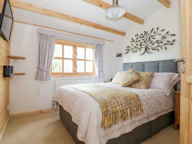 A bedroom with a double bed wooden window and wall decoration at Someplace Else in Diss