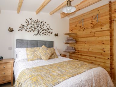 A bedroom with a double bed bedside tables wall art and wooden paneling at Someplace Else in Diss