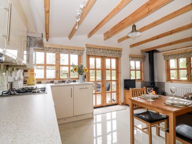 A kitchen and dining area with wooden beams on the ceiling and wood stove at Someplace Else in Diss