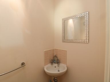 A small bathroom sink with taps and a soap dispenser under a mirror with a tiled backsplash at Beach House in Beadnell