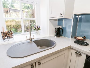 A kitchen sink with a faucet a kettle and a bowl of eggs on the countertop at Crooked Cottage in Kirkbymoorside