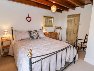 A bedroom with a double bed wooden ceiling and a wooden door at Crooked Cottage in Kirkbymoorside