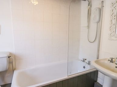 A bathroom with a bathtub a showerhead a sink and a toilet at Crooked Cottage in Kirkbymoorside