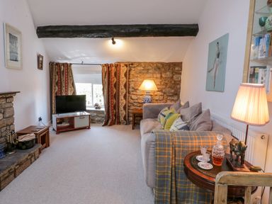 A living room with sofa cushions a lamp and a television at Crooked Cottage in Kirkbymoorside