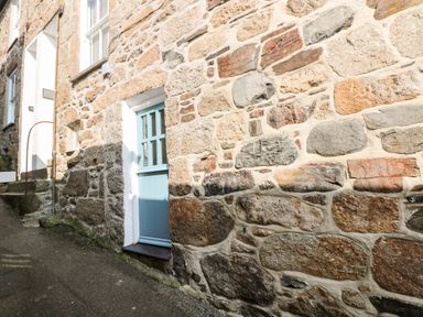 A stone exterior wall with a blue door and window at Mole Cottage in Mousehole