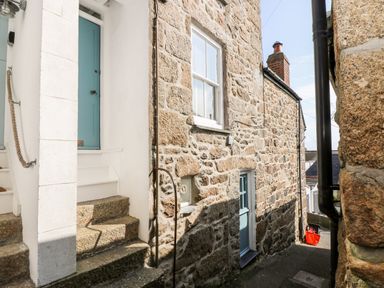 A narrow stone alleyway with two blue doors and stone steps at Mole Cottage in Mousehole