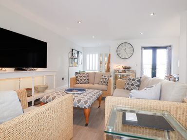 A living room with a television, sofa, and coffee table at Seaspell Beach House, Constantine Bay