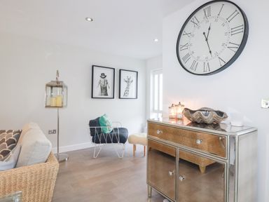 A living room with a clock and artwork at Seaspell Beach House in Constantine Bay