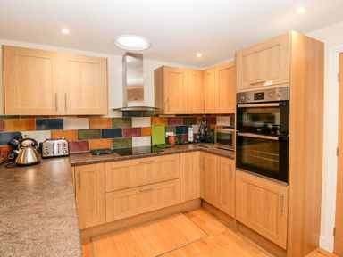 A kitchen with wooden cabinets a dual oven a microwave a kettle and a toaster at Vine Lodge in Kingsbury Episcopi near Martock