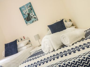 A bedroom with two single beds white rolled towels and blue cushions at Valley Lodge 48 Callington