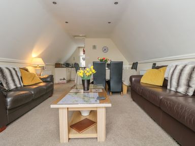 A living room with two sofas a coffee table with yellow flowers and a dining table with chairs at Valley Lodge 48 Callington
