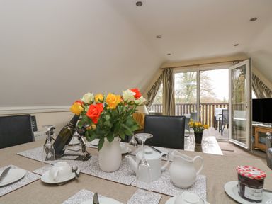 A dining table set with flowers teapot and jam in a room with a balcony door open at Valley Lodge 48 in Callington
